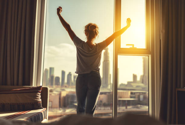 Person stretching calmly by a sunlit window during a morning wellness routine